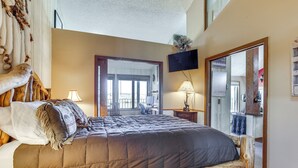 A bedroom with a large bed, a wooden headboard, a TV mounted on the wall, and a mirror. - Walk to Ski Lift & Hiking: Granby Ranch Condo! (Granby)
