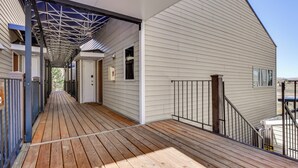 A covered wooden deck with a metal railing, leading to a white building with a door and windows. - Walk to Ski Lift & Hiking: Granby Ranch Condo! (Granby)