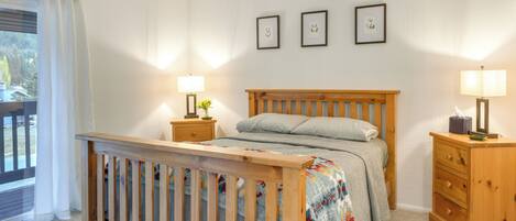 A bedroom with a wooden bed, two bedside tables, a nightstand, and a window with curtains.