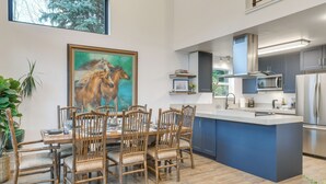 Una cocina moderna con una isla grande, sillas de madera y un cuadro de caballos en la pared.