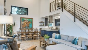 Amplia sala de estar con mesa de comedor, sofás y una escalera.