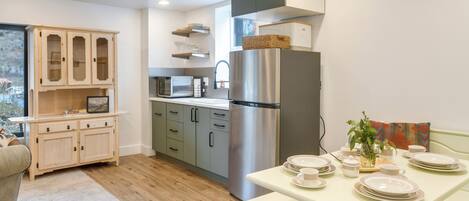Una cocina moderna con un refrigerador de acero inoxidable, armarios de madera y una mesa de comedor dispuesta con platos y tazas.