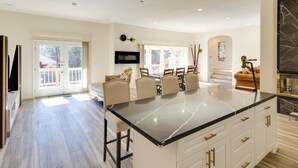 A spacious kitchen with a large island, a dining area with chairs, and a fireplace. - Game Room & Deck: Modern Frazier Park Home! (Pine Mountain Club)
