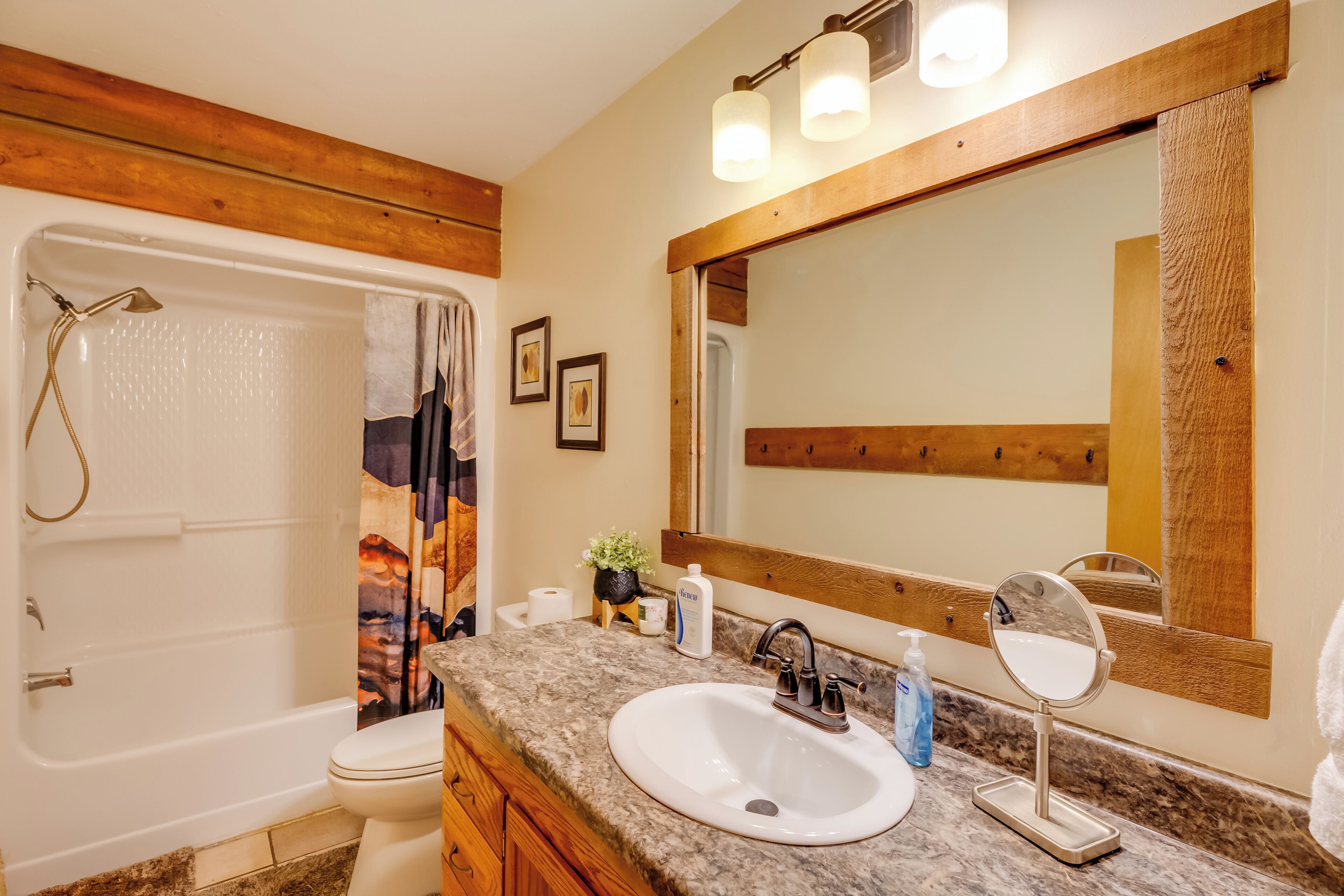 A bathroom with a bathtub, toilet, vanity with a sink and mirror, and a shower curtain.