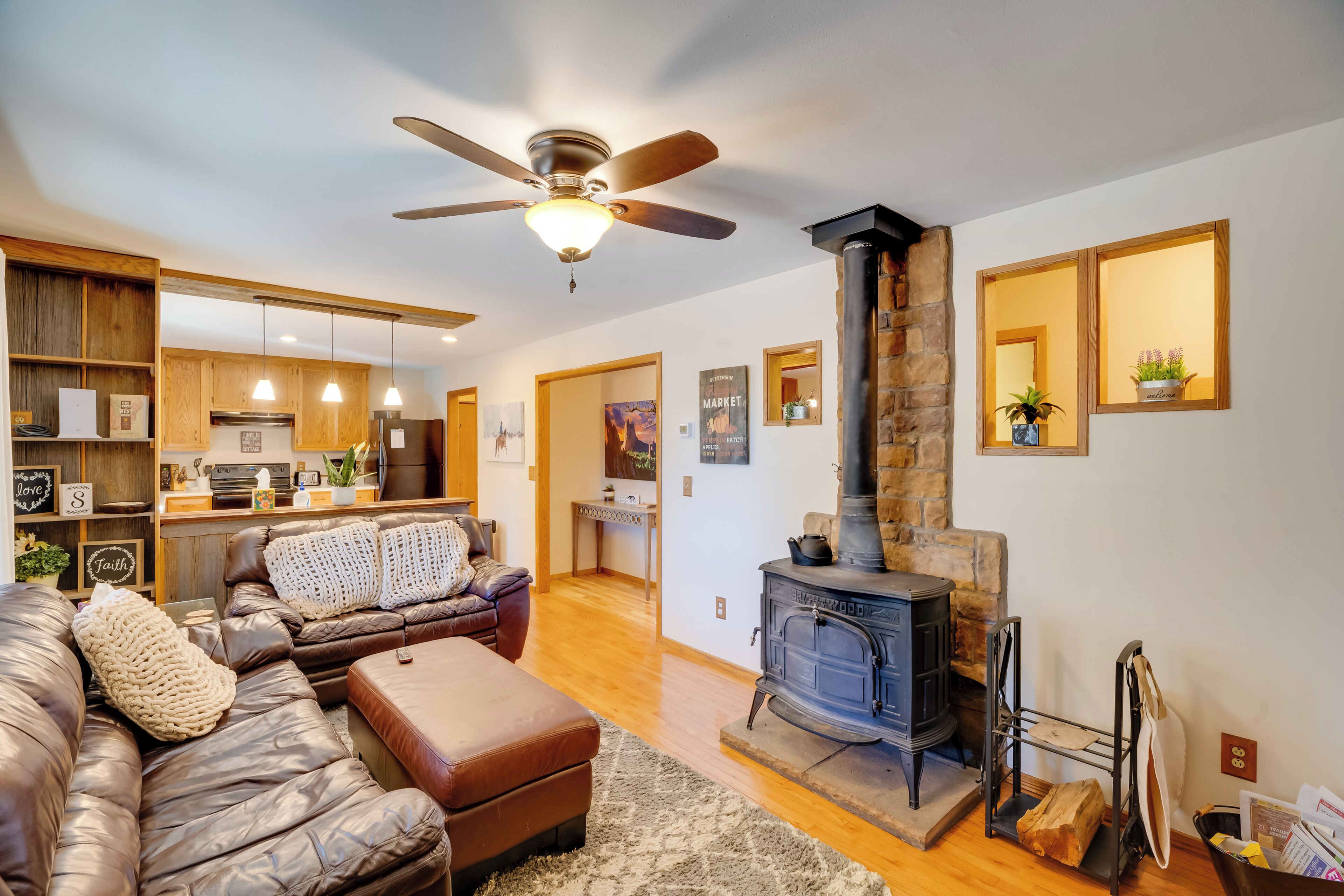A cozy living room with a fireplace, leather furniture, and a kitchen in the background.