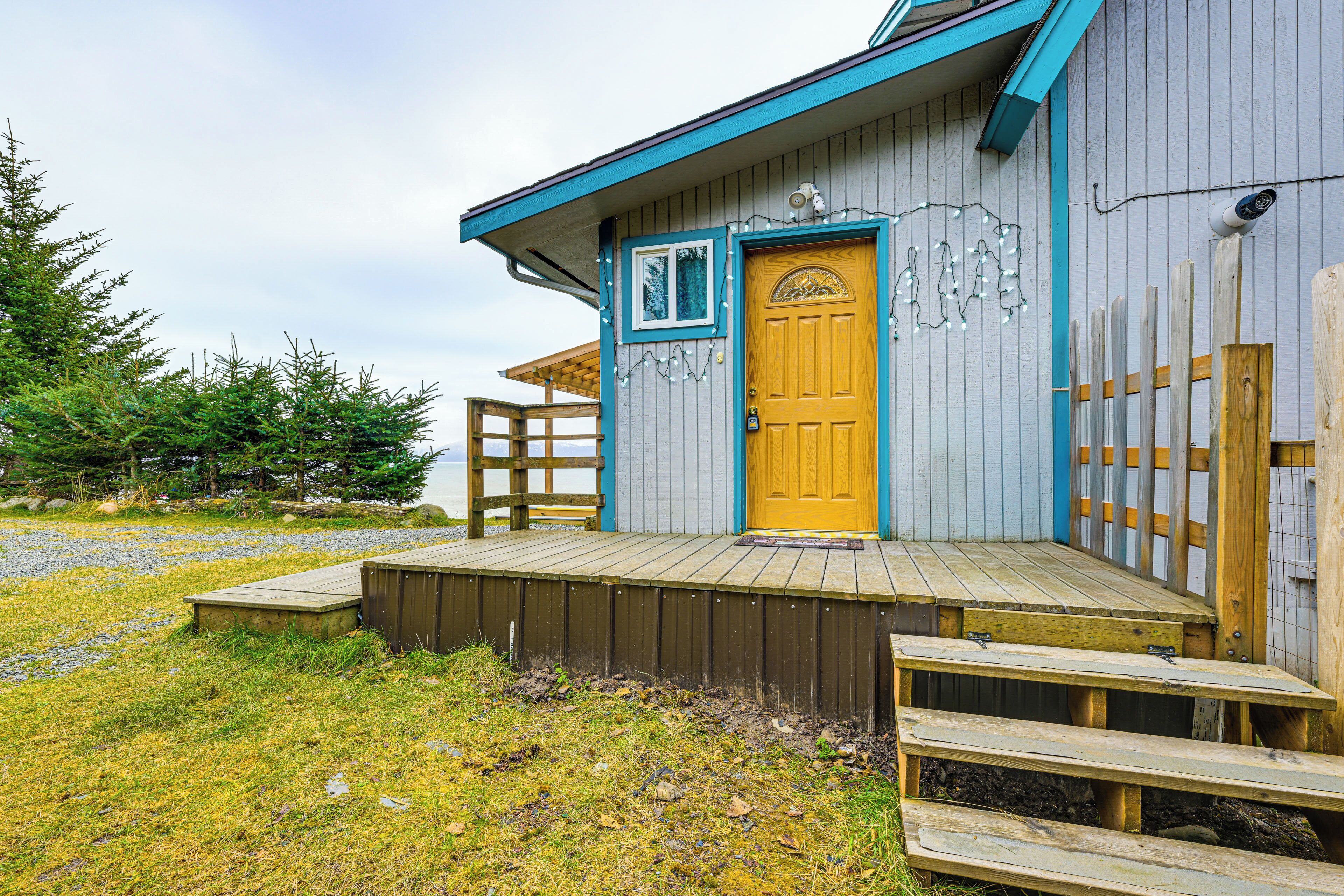 A wooden cabin with a wooden deck, a door, and a small window.
