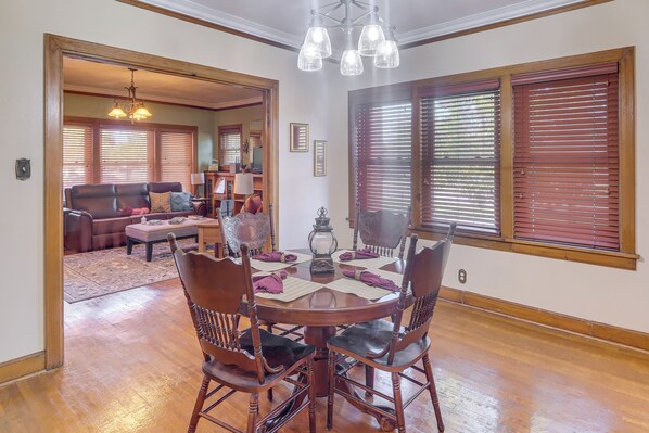 A dining area with a round table, wooden chairs, and a chandelier. - Walk to Main Street: Charming Roswell Home! (Roswell)