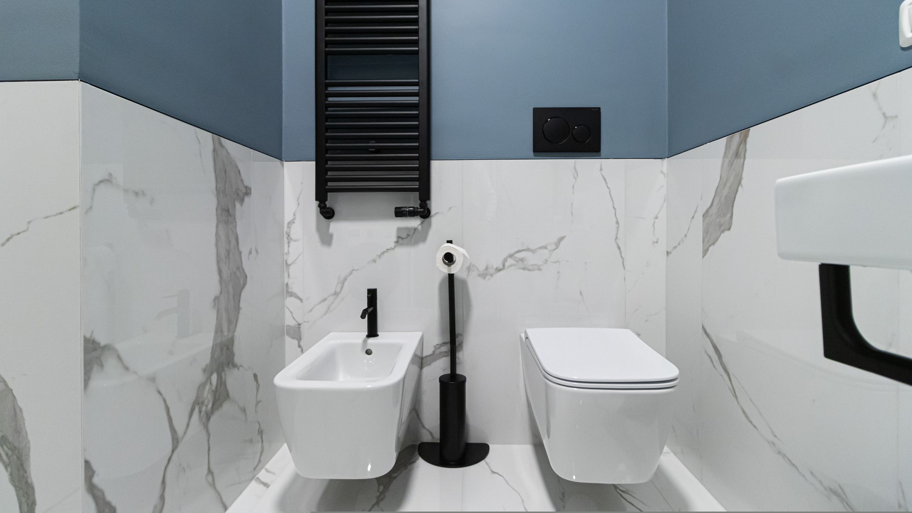 A bathroom with a bidet, toilet, and a towel rack.