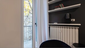 A room with a view of autumn leaves through a window, a radiator, a black chair, and a white shelf with books and a no-smoking sign. - Italianway Collection - Cola Montano 29 B (Milan)