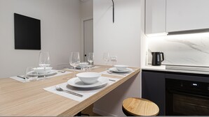 A modern kitchen with a wooden dining table set for four, equipped with white plates, bowls, and wine glasses. - Italianway Collection - Cola Montano 29 B (Milan)