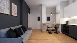 A modern apartment with a grey sofa, a wooden floor, a kitchen with a marble countertop, and a bar area with stools. - Italianway Collection - Cola Montano 29 B (Milan)