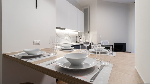 A modern kitchen with a dining area set for a meal. - Italianway Collection - Cola Montano 29 B (Milan)