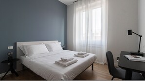 A neatly made bed with white linens and towels, a bedside table with a lamp, and a chair with a magazine. - Italianway Collection - Cola Montano 29 B (Milan)