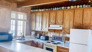 A kitchen with wooden cabinets, a central island, a refrigerator, a stove, and a sink. - Spa & Private Beach | Chalet Natura Versailles (Saint-Côme)