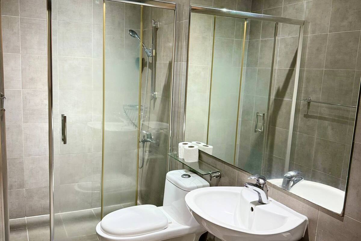 A modern bathroom with a glass-enclosed shower, a pedestal sink, and a toilet.