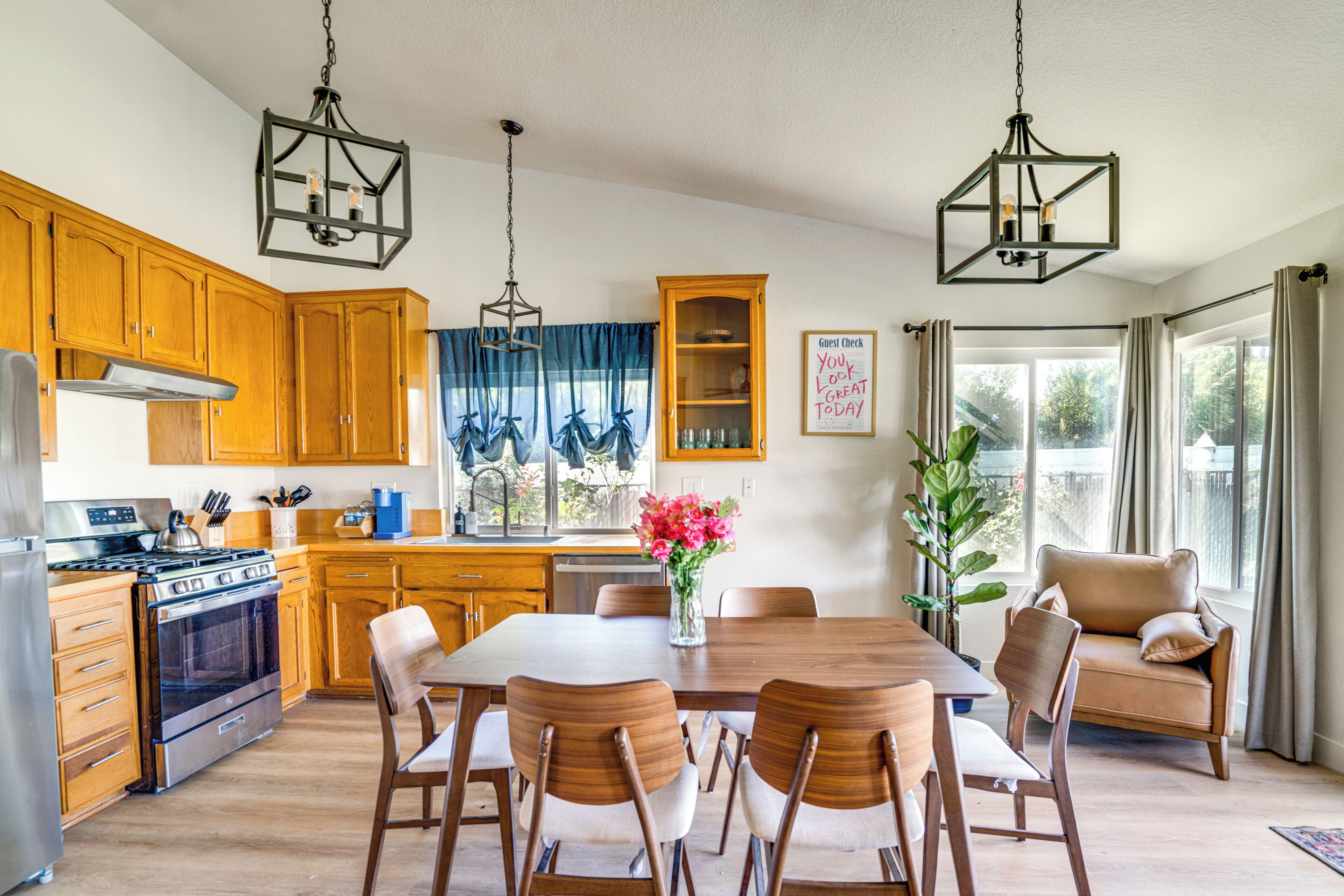 A kitchen with wooden cabinets, a dining table with chairs, a stove, and a chandelier.