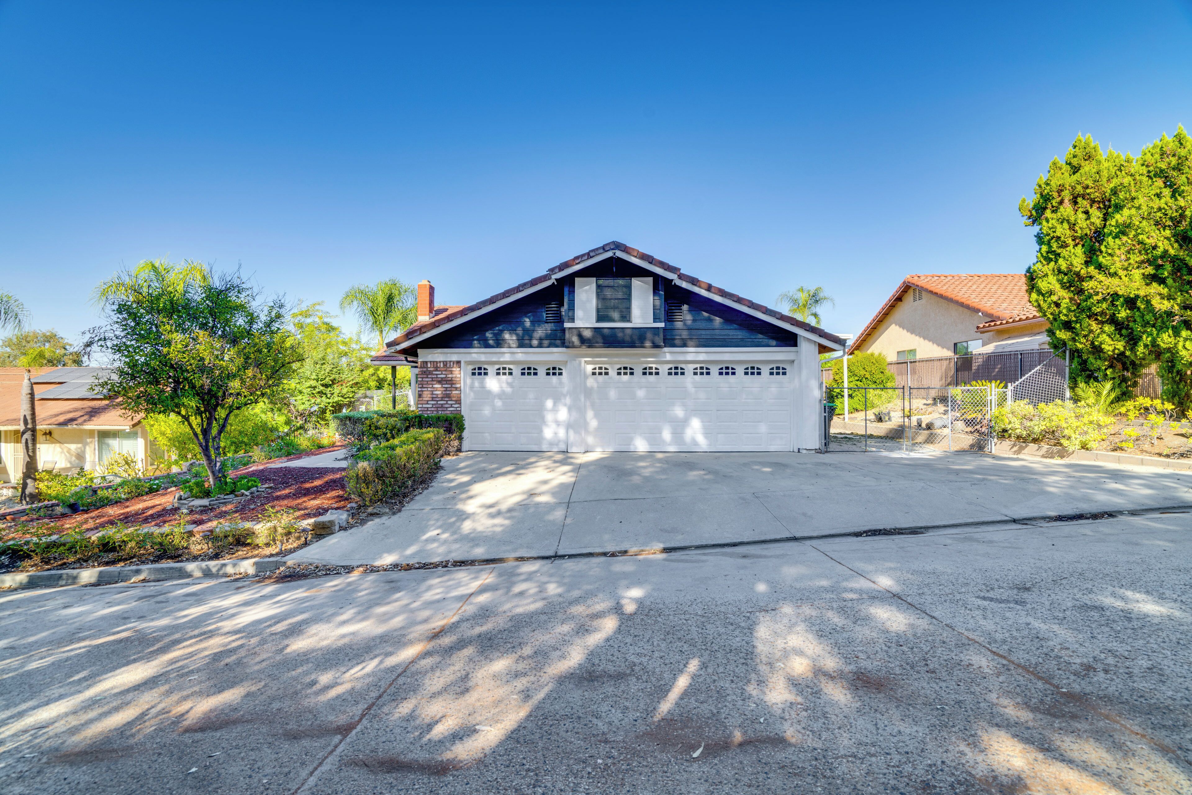 A residential house with a garage, surrounded by trees and a clear sky.