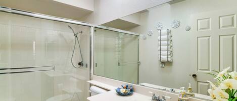 A bathroom with a glass-enclosed shower, a sink with a mirror, and a toilet.