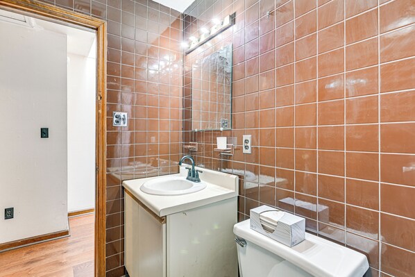 A bathroom with brown tiles, a white sink, and a toilet. - Quiet Catskill Getaway w/ Fire Pit - Near Hiking! (Catskill)