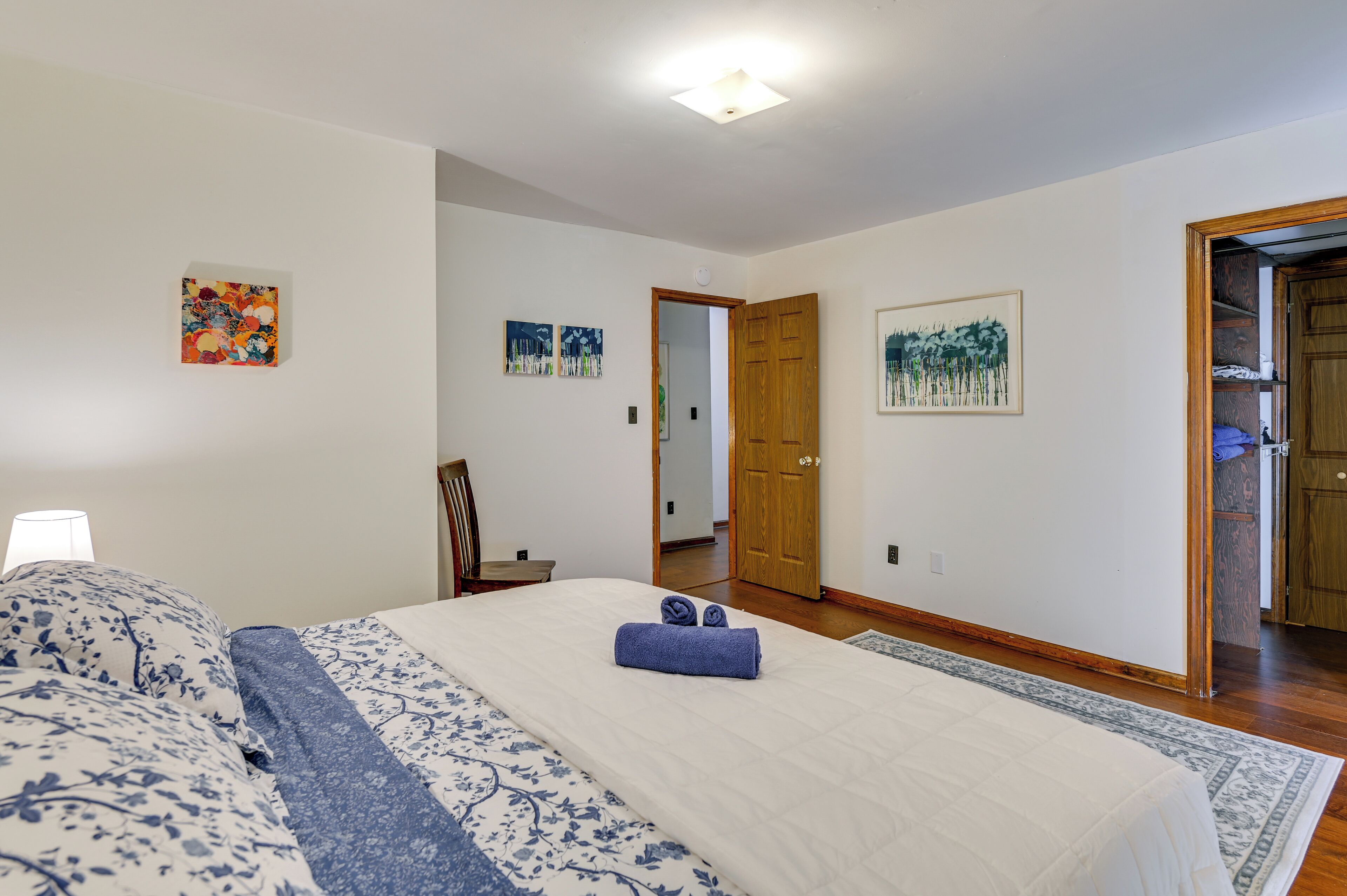 A bedroom with a large bed, a wooden door, and a small table with a chair.