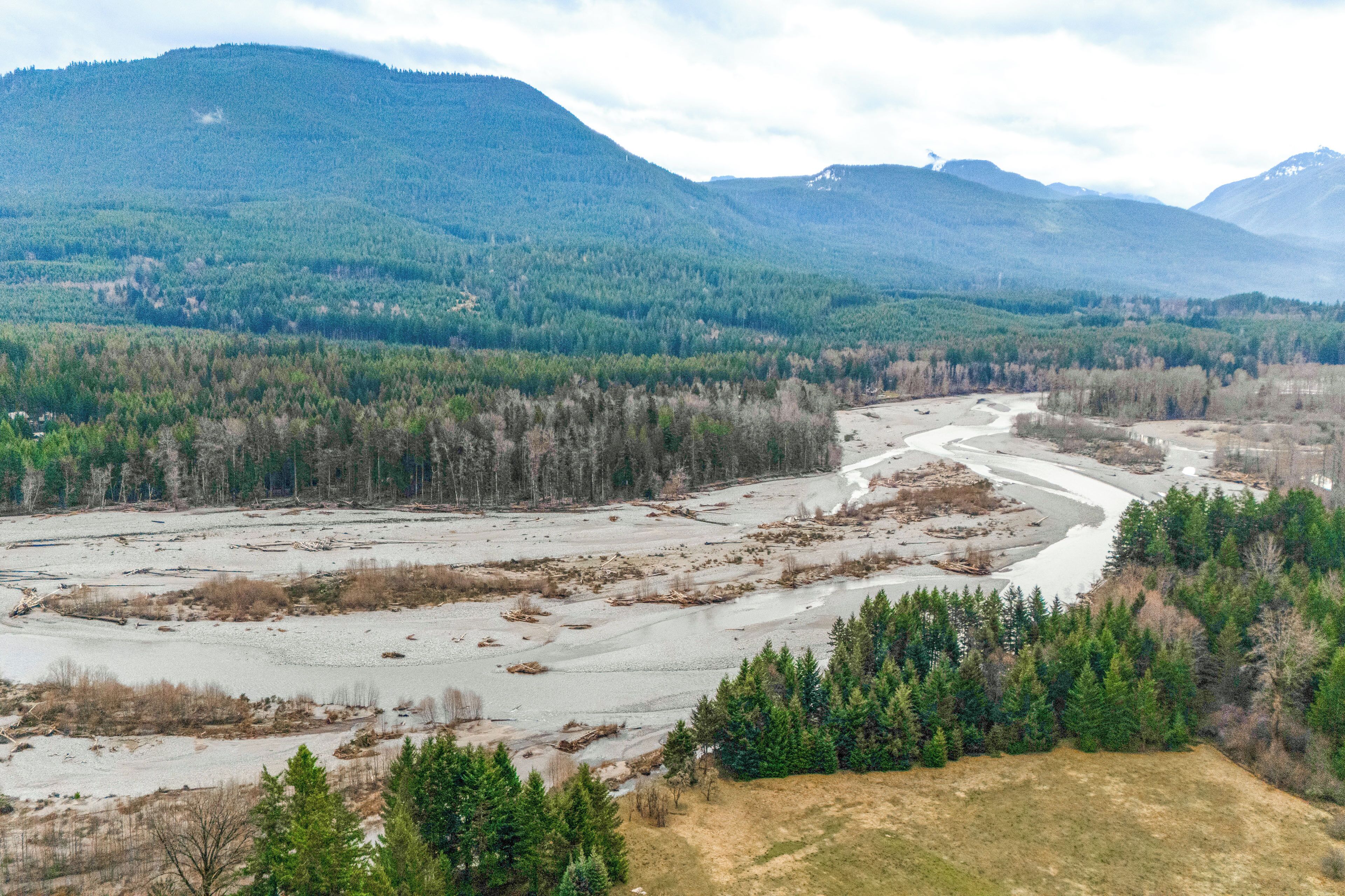 A river winding through a forested valley with mountains in the background.