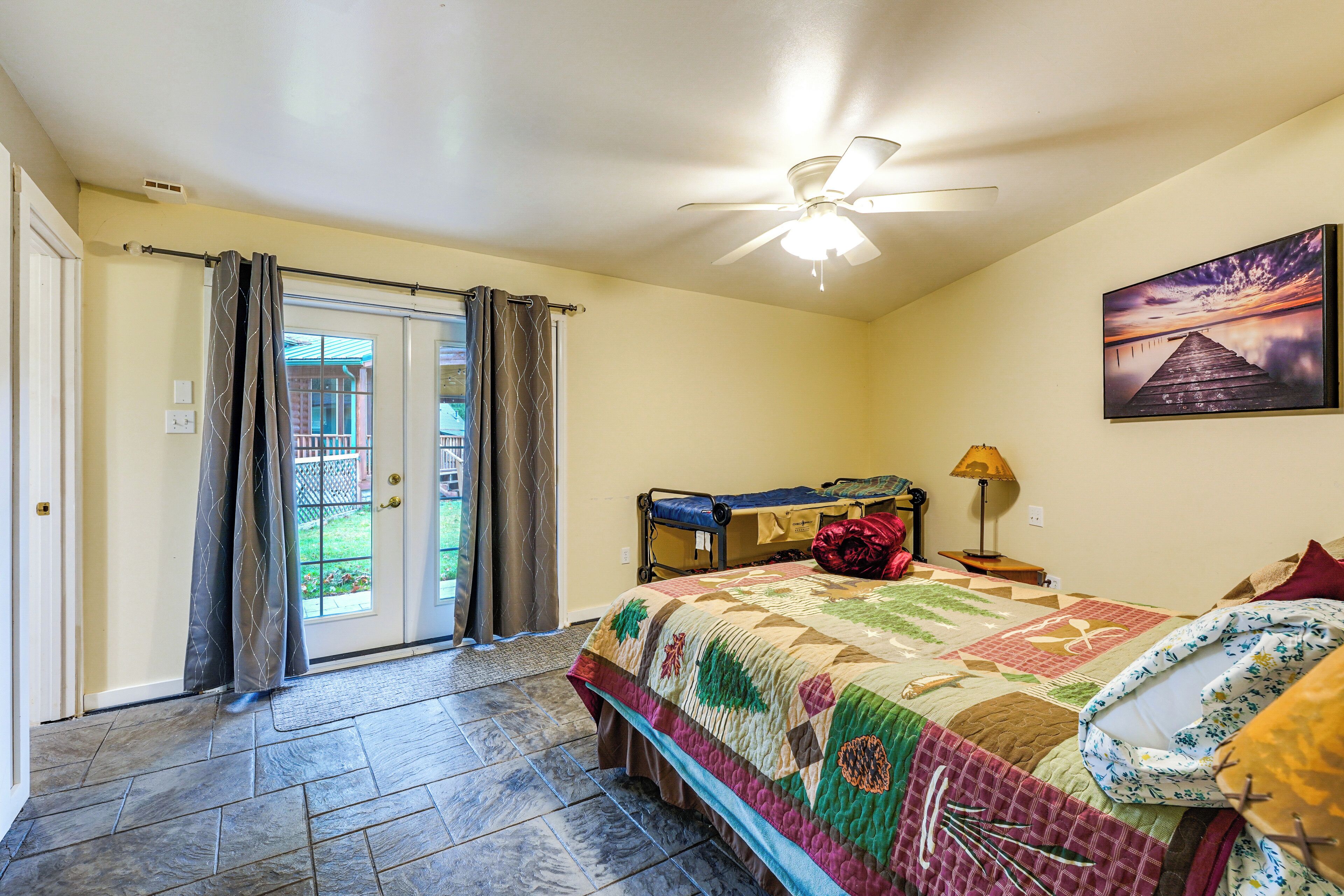 A bedroom with a bed, a ceiling fan, a door leading to a balcony, and a painting on the wall.