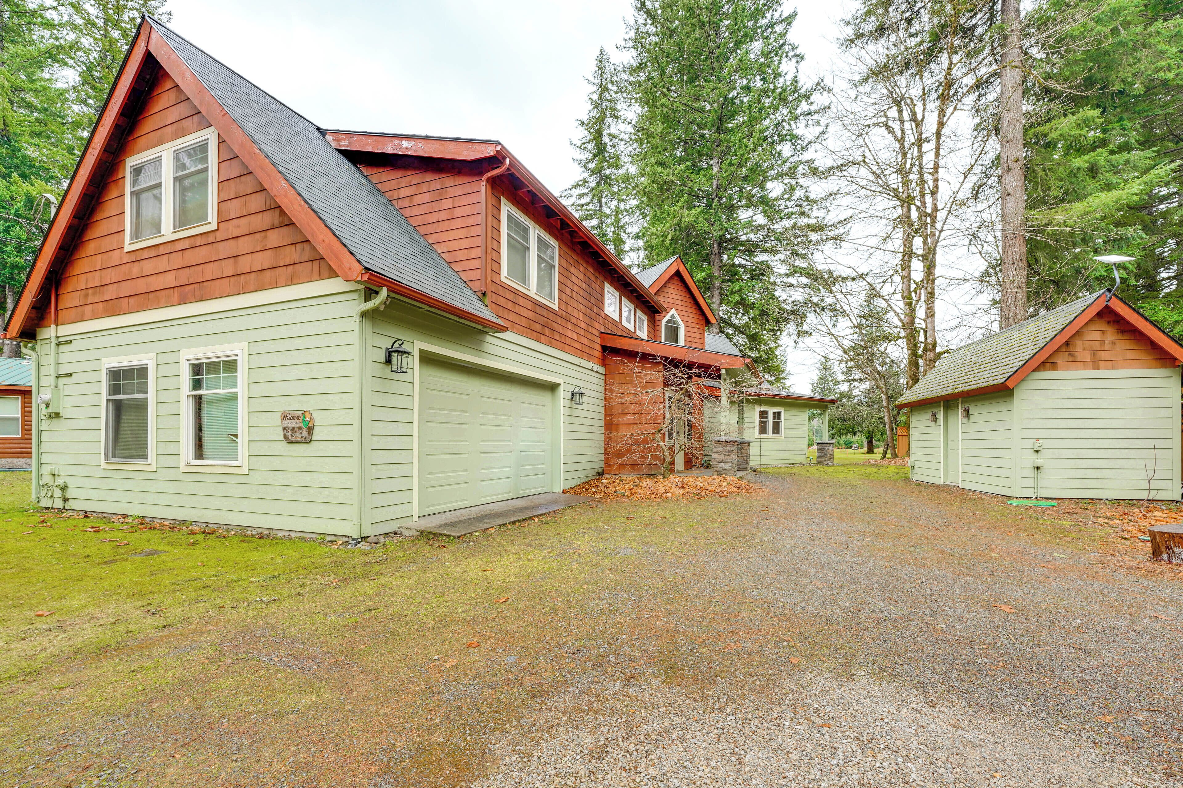 A two-story wooden house with a gravel driveway and a small detached garage.