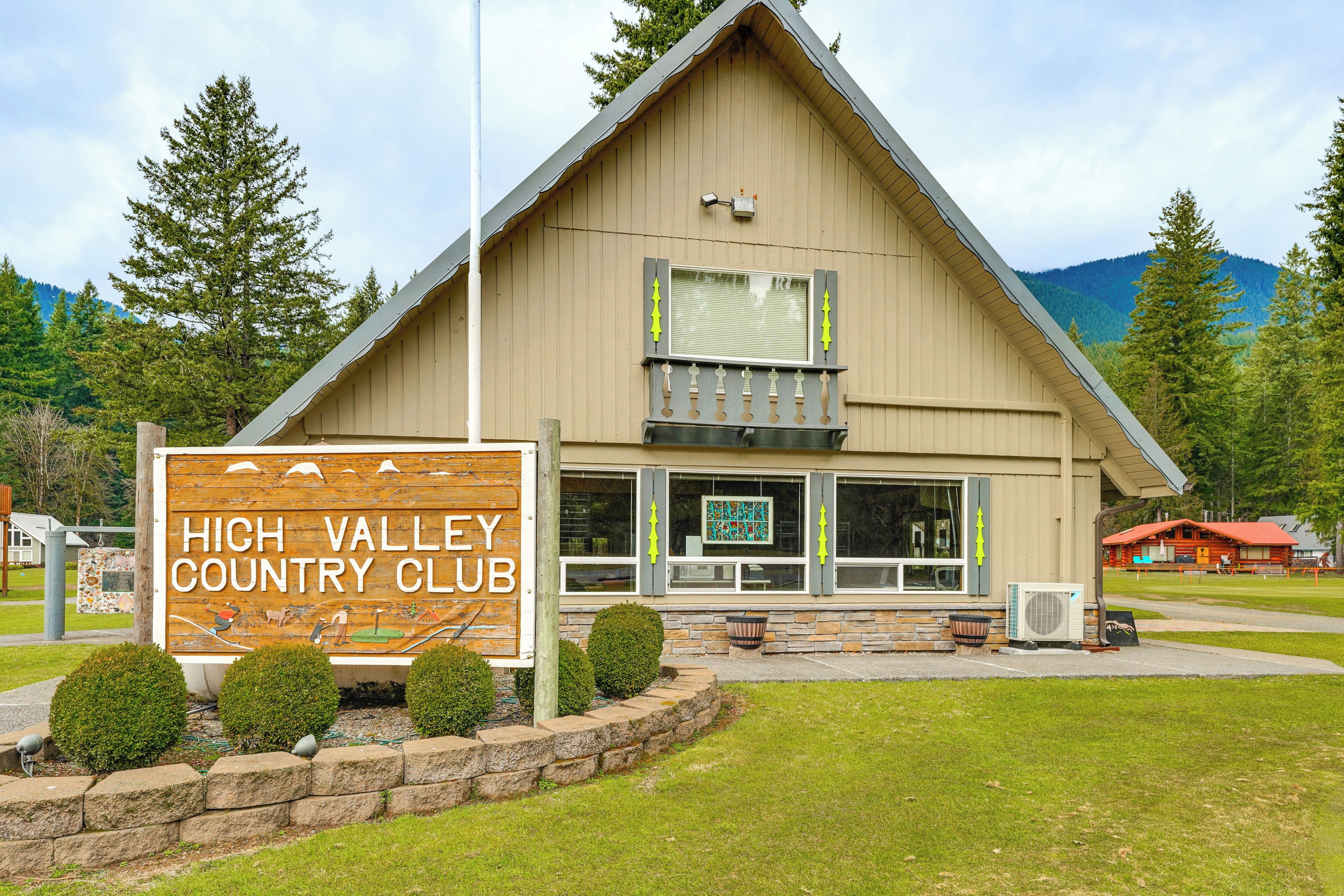 Un bâtiment portant l’inscription « High Valley Country Club », avec une enseigne bien visible, un balcon et un mur de pierres agrémenté d’arbustes.