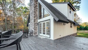 Una casa moderna con rivestimento in pietra, ampie finestre e un patio in legno con mobili da esterno.