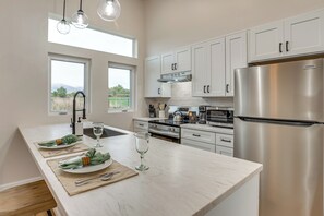 A modern kitchen with white cabinets, stainless steel appliances, and a large island with a glass top. - Wineries & Farm Fresh Harvest: Chic Palisade Gem! (Palisade)