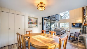 A spacious living area with a wooden dining table, comfortable seating, a staircase, and a bookshelf. - Walk to Liberty Mountain: Lake-view Ski Retreat! (Fairfield)