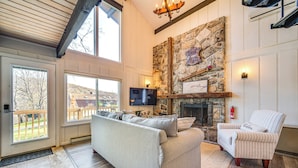 A cozy living room with a stone fireplace, a comfortable sofa, and a television. - Walk to Liberty Mountain: Lake-view Ski Retreat! (Fairfield)