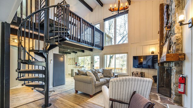 A spacious living area with a modern staircase, a fireplace, and a cozy seating arrangement. - Walk to Liberty Mountain: Lake-view Ski Retreat! (Fairfield)