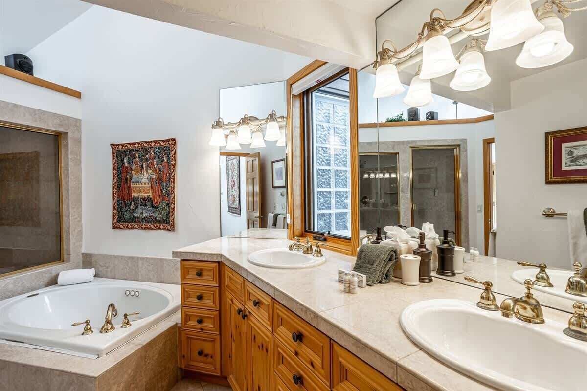 Un baño con dos lavamanos, un espejo grande y una bañera.
