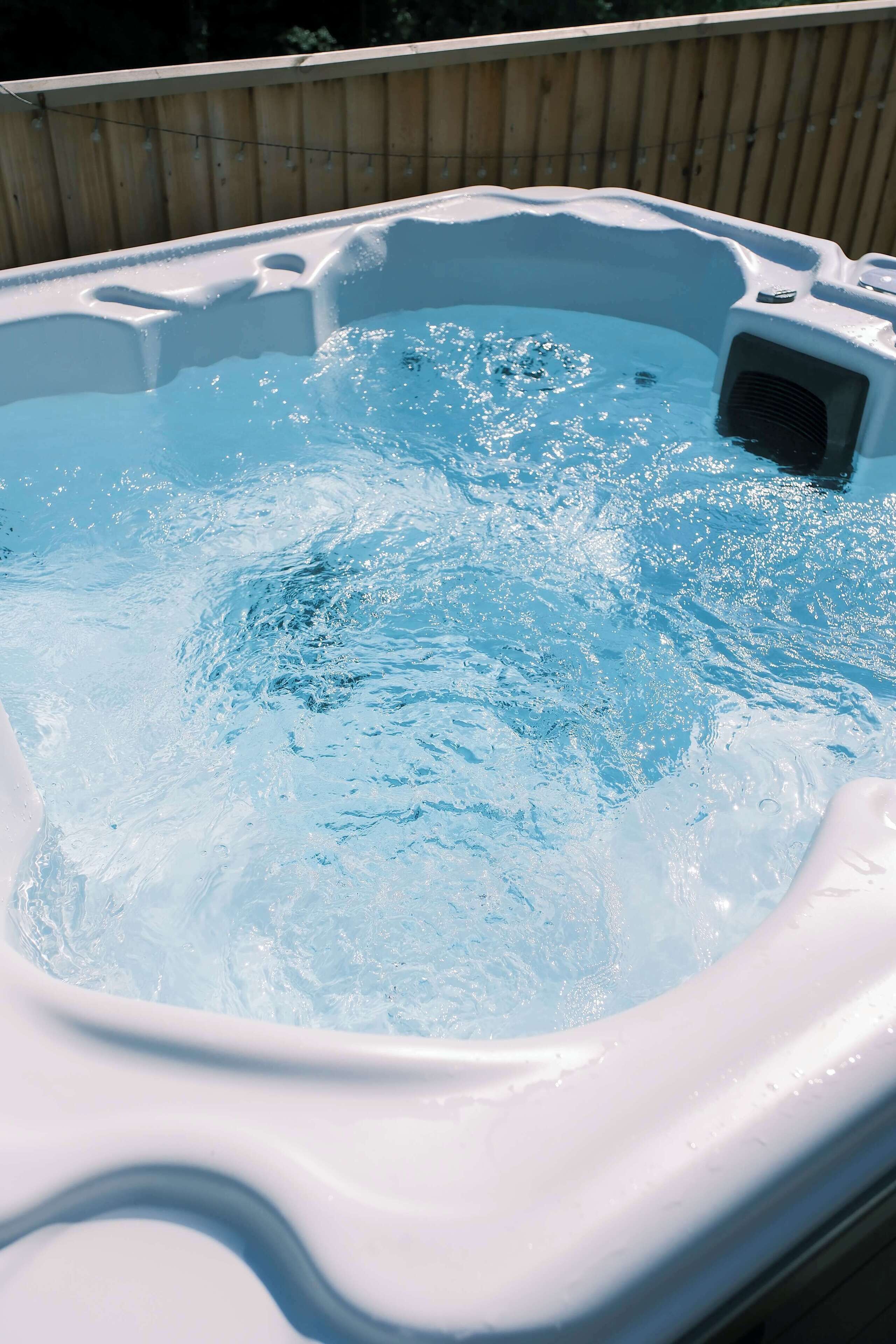 Boblende hottub omgivet af et træhegn.