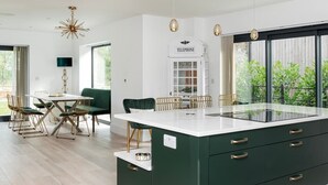 Une cuisine moderne dotée d’un grand îlot central, d’un coin repas avec une table et des chaises, et d’une cabine téléphonique.