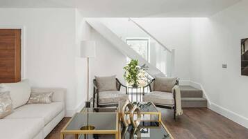 Un salon moderne comprenant un canapé, deux fauteuils, une table basse et un escalier menant à un niveau supérieur.