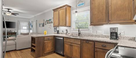A modern kitchen with wooden cabinets, granite countertops, and a dishwasher.