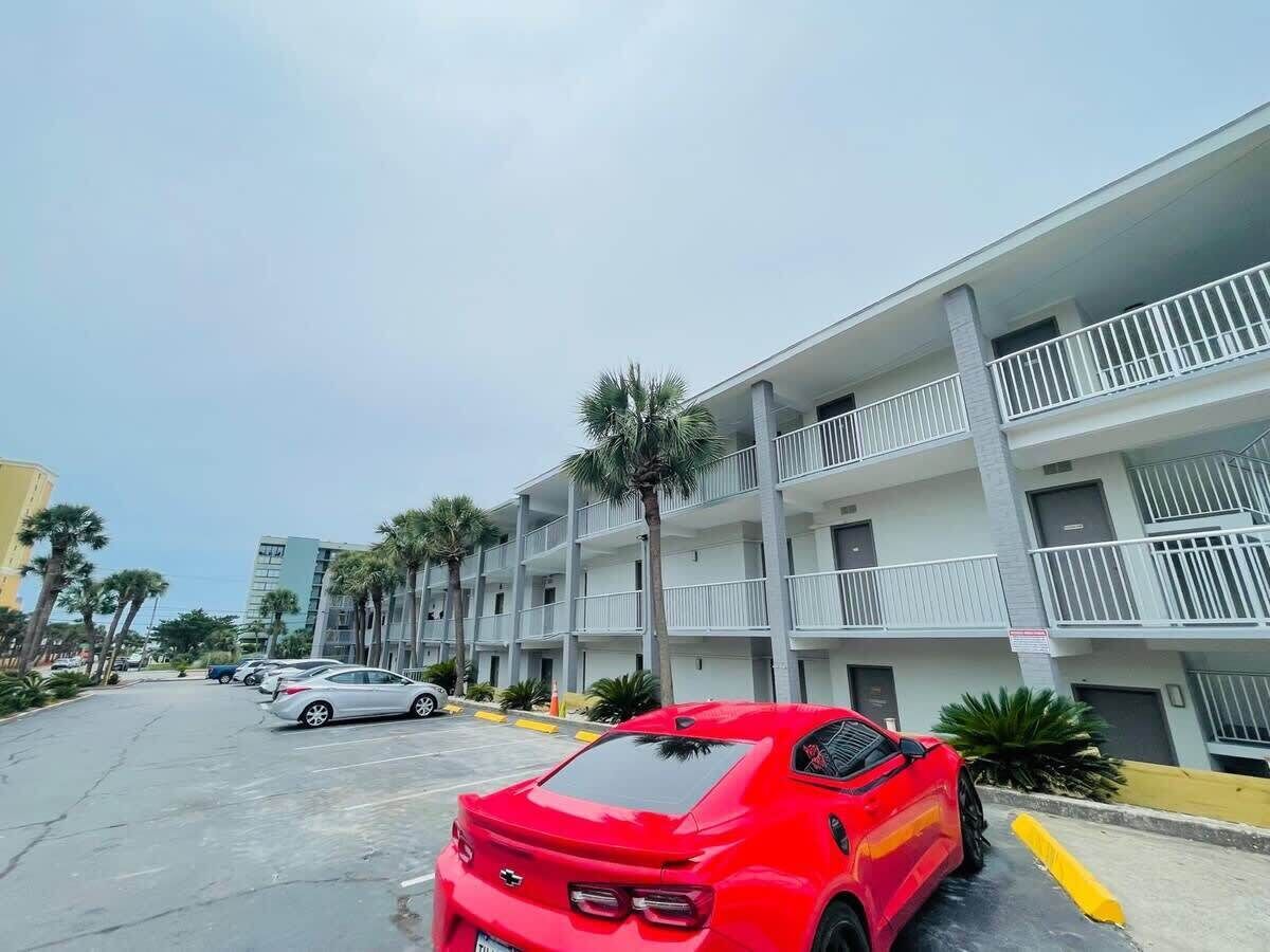A multi-story building with balconies and a parking lot.