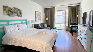 A bedroom with a large bed, a sofa, a desk with a TV, and a sliding glass door to the outside. - SJ9 Bright studio walk to the beach (Myrtle Beach)