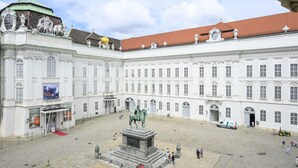 A large, historic building with a central courtyard, a statue, and a red carpet leading to the entrance. - Palais Palffy Hotel Suite in Central Vienna (Vienna)