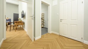 A hallway with wooden flooring, white doors, and a dining area with a table and chairs. - Palais Palffy Hotel Suite in Central Vienna (Vienna)