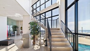 A modern interior with a staircase leading to a balcony overlooking a pool.