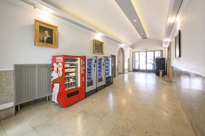 Corridors feature framed artwork and vending machines, including a Pierre Baguette machine, leading to a glass door.