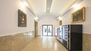 A hallway with marble flooring, framed artwork on the walls, and vending machines.
