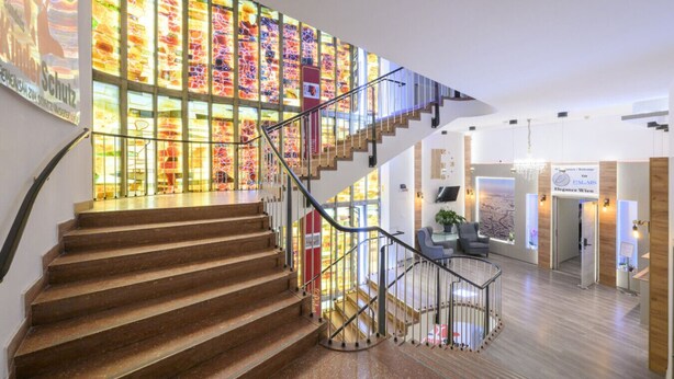 A modern hotel interior with a spiral staircase, a stained glass wall, and a reception area.