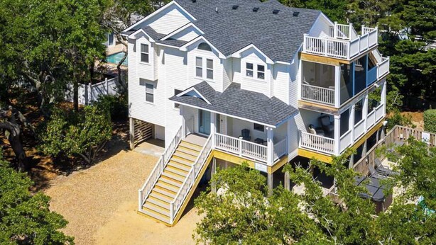 A multi-story house with a balcony, surrounded by trees and a clear view of the ocean. - Oceanside Duck Retreat w Pool, Spa, Mins to Beach! (Duck)