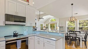 A modern kitchen with white cabinetry, a stainless steel range, and a large island. - Oceanside Duck Retreat w Pool, Spa, Mins to Beach! (Duck)