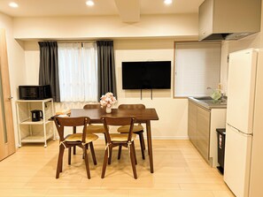 A compact kitchen with a dining table and chairs, a television, and a refrigerator. - RUKA (Osaka)