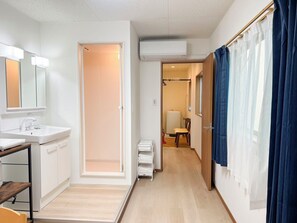 A modern bathroom with a sink, mirror, and shower area. - RUKA (Osaka)